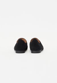 Zwarte suède loafers met een lage hak, met een gladde textuur en een eenvoudig achterontwerp. Gevoerde binnenkant voor comfort en duurzaamheid.