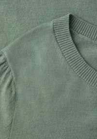 Pull tricoté vert sauge doux avec col en V et détail de manche bouffante froncée sur l'épaule gauche.