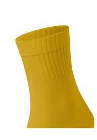 Gelbe gerippte Socke mit hohem Bündchen und glatter Textur, entworfen für Komfort und Stil.