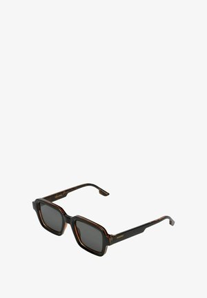 Lunettes de soleil carrées avec une monture en motif écaille de tortue, verres sombres et branches noires élégantes. Gravure de marque notable sur les tempes.