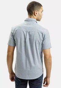 Koszula w kratę z krótkim rękawem w jasnoniebieskim i białym kolorze, z kołnierzykiem typu spread i luźnym krojem. Z tyłu znajduje się karczek oraz subtelne zaszewki.