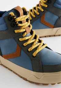 Hoge sneakers met een blauwe synthetische bovenkant en grijze accenten, bruin lederen details en gele gespikkelde veters. Gelaagde rubberen zool.