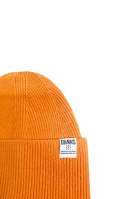 Orange ribbed knit beanie with a folded brim. Features a white label with black text on the side. Texture appears soft and warm.