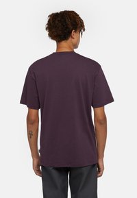 Lila t-shirt i bomull med kort ärm och rundad halsringning; enkel design, inga synliga grafik eller mönster. Bakvy visas.