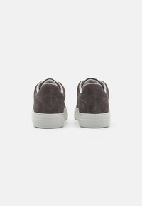 Gray suede sneakers with white rubber soles. Rounded back with stitching detail and a soft interior lining. Minimalist design, low-profile style.