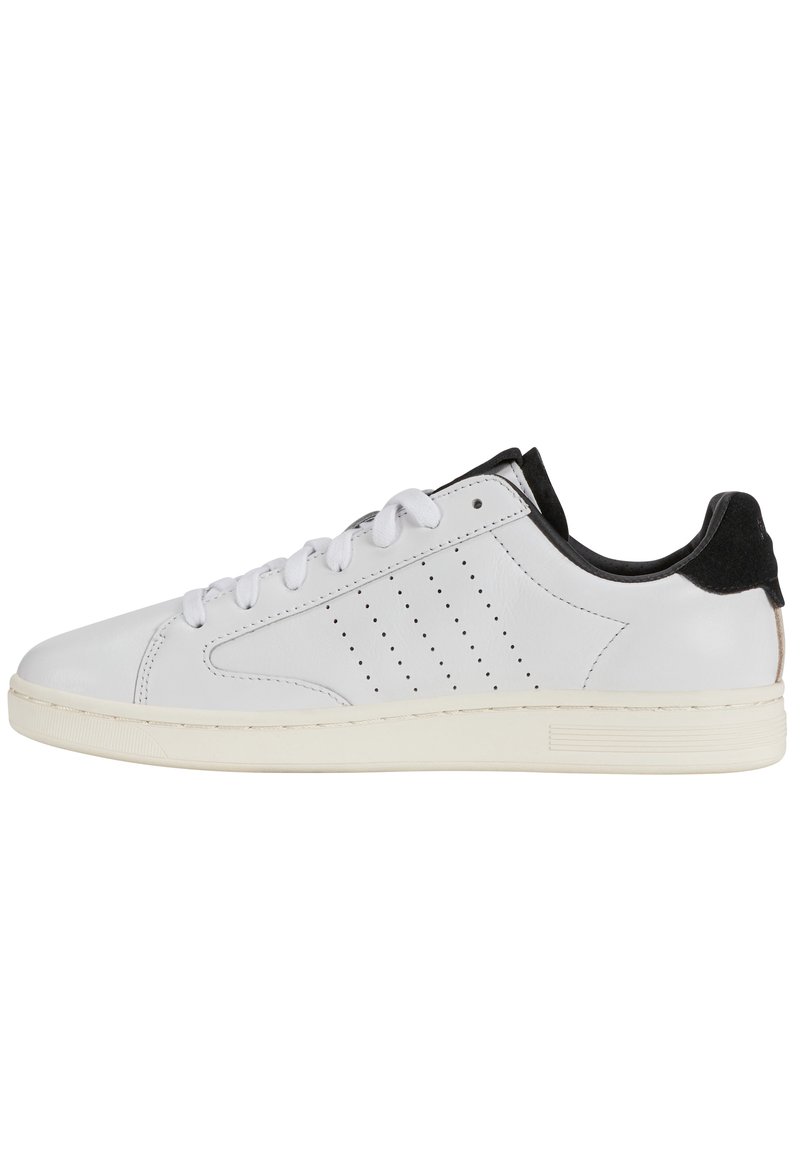 Sneaker bianca in pelle con accentuazione in camoscio nero sul tallone, punta rotonda, lacci frontali, dettagli perforati sui lati e suola in gomma beige.