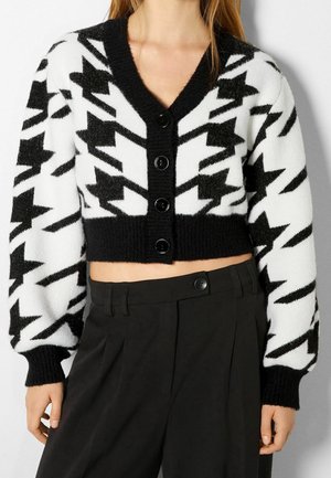 Cardigan cropped en noir et blanc avec un motif pied-de-poule, en tissu tricoté, col en V et cinq boutons noirs à l'avant.