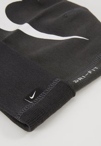 Calza in tessuto Dri-FIT nera con logo Nike bianco, caratterizzata da un design a maglia testurizzata e cuciture rinforzate al polsino.