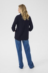 Navy-blaues Oversized-Hemd mit aufgerollten Ärmeln, weicher Textur, kombiniert mit hellblauen weit geschnittenen Jeans, die einen lockeren Sitz und lässigen Stil zeigen.