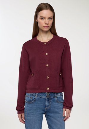 Cardigan lavorato a maglia color bordeaux con collo rotondo, bottoni frontali e due tasche anteriori. Presenta dettagli con bottoni dorati e maniche lunghe.
