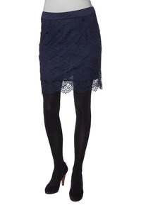 La skirta natt blå med en scalloped fåll, som har en slät midja och en intrikat blommönster. Bärs med svarta strumpbyxor och klackskor.