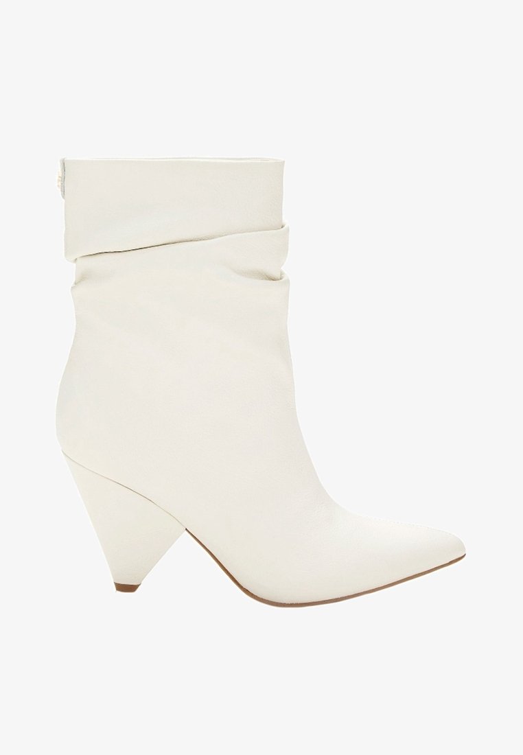 Bottine en cuir blanc avec bout pointu, tige souple et talon conique épais.