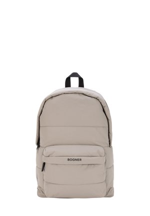 Mochila acolchada color beige claro con bolsillo frontal con cremallera y asa negra, con la marca "Bogner" en el bolsillo frontal.