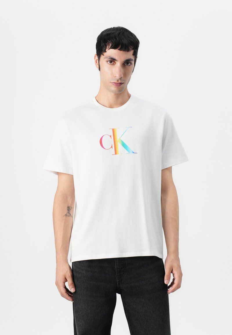 Balta medvilninė marškinėliai su daugiaspalviu "ck" logotipu priekyje. Klasikinis apvalus kaklas, trumpomis rankovėmis, laisvas pritaikymas.