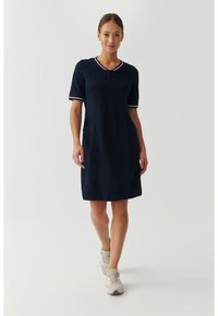 Robe bleu marine à manches courtes avec un décolleté en V, bordure blanche et deux poches avant. Fabriquée dans un tissu doux ; longueur genou avec une coupe décontractée.