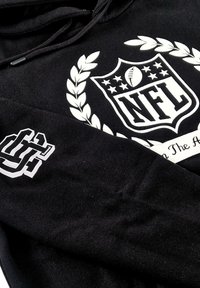 Black hoodie featuring a large white NFL logo with a laurel design and a smaller graphic on the sleeve. Fabric appears soft and textured.