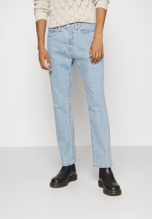Light blue denim jeans with a straight leg cut, featuring five pockets and visible stitching. Worn with black ankle boots.
