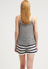 Yksivärinen, kukkakuosisia hihattomia yläosia tummansinisessä ja valkoisessa, yhdistettynä vaaleisiin shortseihin, joissa on tummansiniset raidat. Kevyt kangas, rento istuvuus.