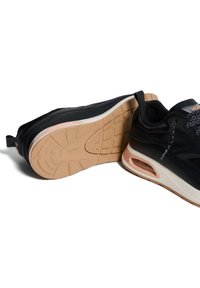 Scarpe da atletica nere con tomaia texturizzata, dotate di una soletta intermedia chiara e suola in gomma. Accentuate da un'unità d'aria trasparente e lacci decorati.