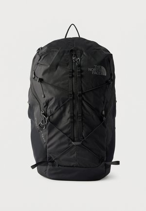 Black North Face backpack with vertical front zipper, bungee cord system, and top handle on a plain white background.
