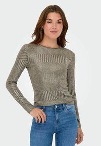 Langermige metallic gouden en zilveren ribbed top met een ronde halslijn en een fitted ontwerp, gecombineerd met blauwe denim jeans.