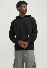 Black hoodie with a kangaroo pocket, made from soft cotton blend. Features ribbed cuffs and hem, with a subtle logo tag on the front.