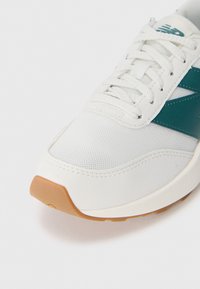 Weiße Sneaker mit türkisfarbenen Akzenten, aus Mesh-Gewebe, mit strukturiertem Obermaterial und Gummisohle mit hellbraunem Absatz. Schnürdesign mit verstärkten Ösen.