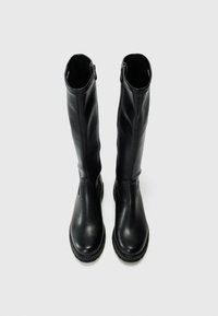 Bottes noires montantes en cuir lisse, avec un bout arrondi et une fermeture éclair latérale, dotées d'une semelle texturée pour une meilleure adhérence.