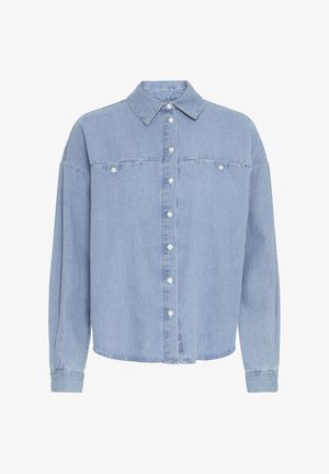 Camicia in denim azzurro chiaro con chiusura a bottoni, maniche lunghe, colletto a punta e due tasche sul petto. Il tessuto appare morbido con una leggera texture.