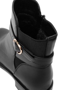 Czarne skórzane botki za kostkę z fabriczną wstawką, z metalowym zapięciem w złotym odcieniu i puszystym wnętrzem. Gładka tekstura, zaokrąglony kształt.