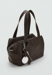 Donkerbruin leren handtas met dubbele schouderbanden, voorzak met ritssluiting en een ronde zilveren sleutelhanger charm die aan een haakje is bevestigd.