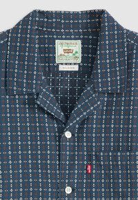 Marineblauwe shirt met een relaxed kraag, bloemenprint in wit en roest, frontzak en knoopsluiting met Levi's label aan de onderkant.