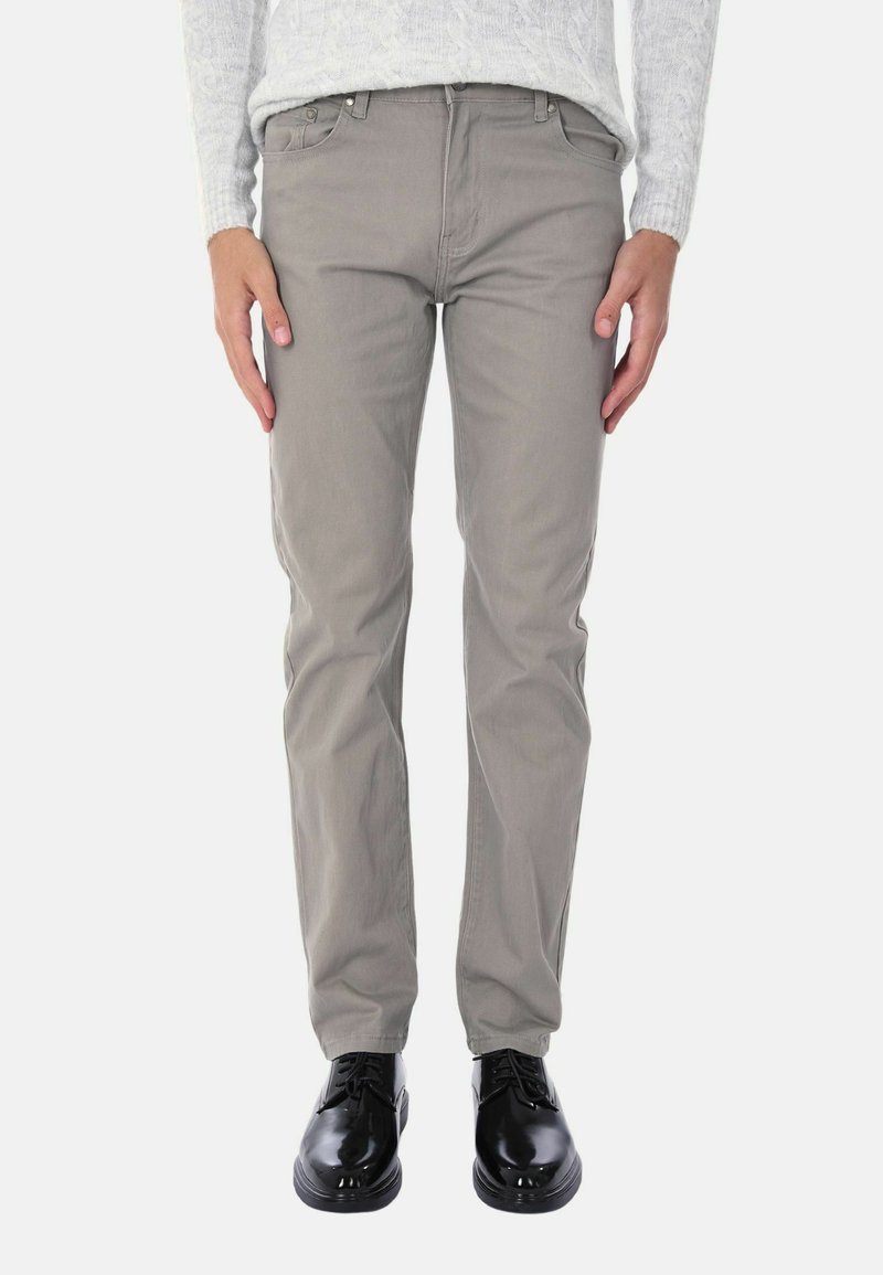 Pantaloni grigi chiari in stoffa di cotone, con un design slim fit, cinque tasche e chiusura con bottone. Indossati con scarpe nere.