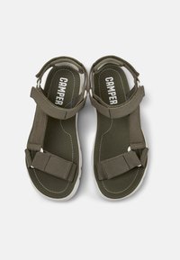 Olivgröna sandaler med justerbara remmar, vita sålar och kontrasterande sömmar. Har en vadderad sula för komfort.