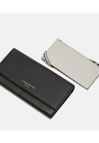 Cartera de cuero negro con una textura suave y un logo plateado; acompañada de un tarjetero gris claro con un diseño minimalista.