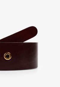 Bordeauxleren riem met een gladde textuur, voorzien van een gouden accentring en een verlengd uiteinde voor het vastmaken. Eenvoudig, rond ontwerp.
