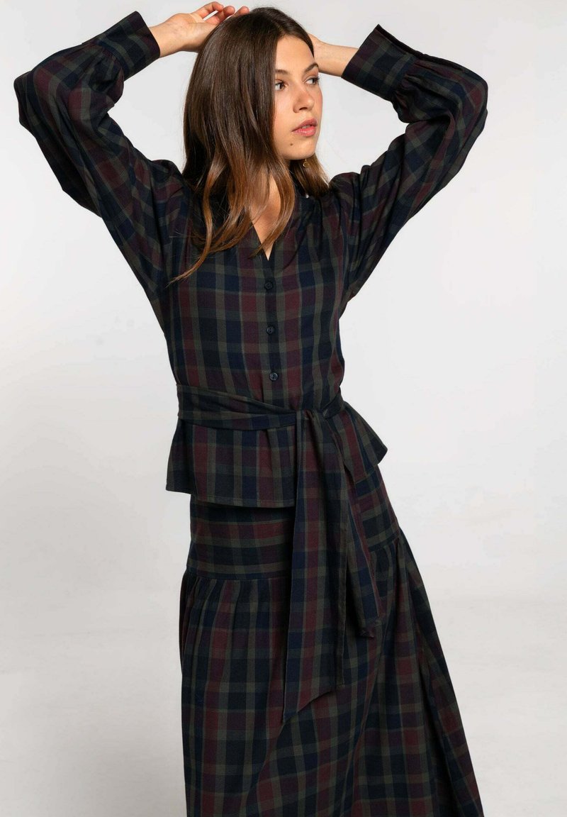 Vestido de camisa de cuadros abotonado en verde oscuro y burdeos, con cintura atada y mangas abullonadas. Tejido suave con un diseño de falda fluida y en capas.