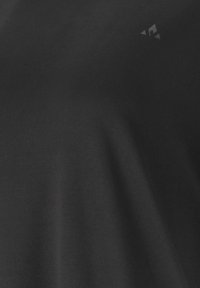 Schwarzes Adidas-Sportshirt mit kleinem weißen Adidas-Logo nahe dem Halsausschnitt auf glattem Stoff.