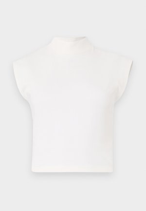 Haut court blanc avec un col montant haut et des manches larges et angulaires. Fabriqué en tissu lisse, sans motifs ni embellissements visibles.