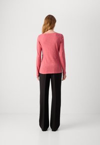 Garās piedurknes, brīvā stilā, augšdaļa izbalējušā korallkrāsā, izgatavota no mīksta, teksturēta auduma. Saskaņota ar augsto jostasvietu melnām biksēm.