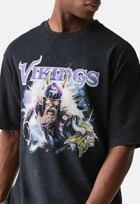 Schwarzes Baumwoll-T-Shirt mit einem bunten Wikinger-Design, das einen mit einem Hornhelm versehenen Wikinger zeigt, umgeben von Blitzeffekten und dem Wort "Vikings" in Lila.