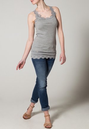Szary top na ramiączkach z prążkowanej tkaniny, z koronkowym wykończeniem przy dekolcie i hemie, zestawiony z dopasowanymi niebieskimi dżinsami i beżowymi sandałami.