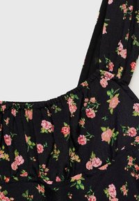 Kukkamekko, jossa on musta kangas, jossa on vaaleanpunaisia ja vihreitä kukkakuvioita, joustava rypytetty kaula-aukko ja ohuet olkaimet.