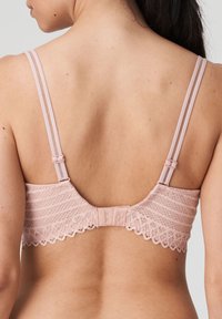 Różowy koronkowy stanik z regulowanymi ramiączkami, z teksturowanym wzorem i falistymi brzegami, pokazany z tyłu. Widoczna zapięcie na haftek.