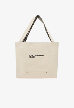 Sac fourre-tout en toile beige avec une poche avant portant l'étiquette "KARL LAGERFELD JEANS" et des anses noires à motif.