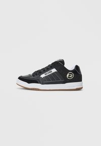 Sneaker nera bassa con suola bianca, marchio "Globe" di lato e suola in gomma, mostrata dal lato esterno su uno sfondo neutro.