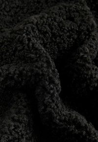 Schwarzer Fleece-Stoff mit einer strukturierten Oberfläche, die kurze, weiche Schlaufen und eine leicht glänzende Oberfläche aufweist, die in einer zerknitterten Anordnung arrangiert ist.