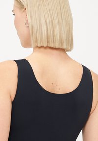 Musta ilmanhiha-bikini, jossa on kuppi takana. Sujuva pinta, jossa on hieman kiiltoa ja minimaalinen ommelkoristelu.