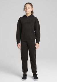 Svart hoodie med framficka och tonalt logotyp, kombinerad med matchande svarta sweatpants. Outfitten har ribbade ärmslut och en enkel design.