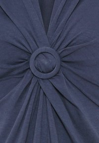 Marineblaues Textil mit verdrehten Details in der Mitte, das einen runden Ringakzent aufweist. Weiche Textur mit Falten, die von der Mitte ausstrahlen.